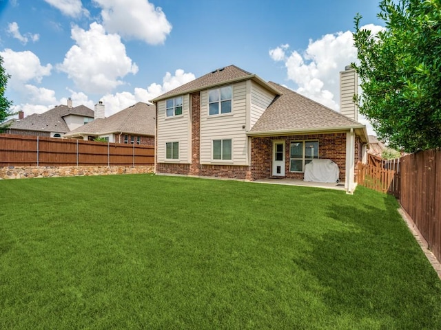 back of property featuring a fenced backyard, a chimney, a yard, a patio area, and brick siding