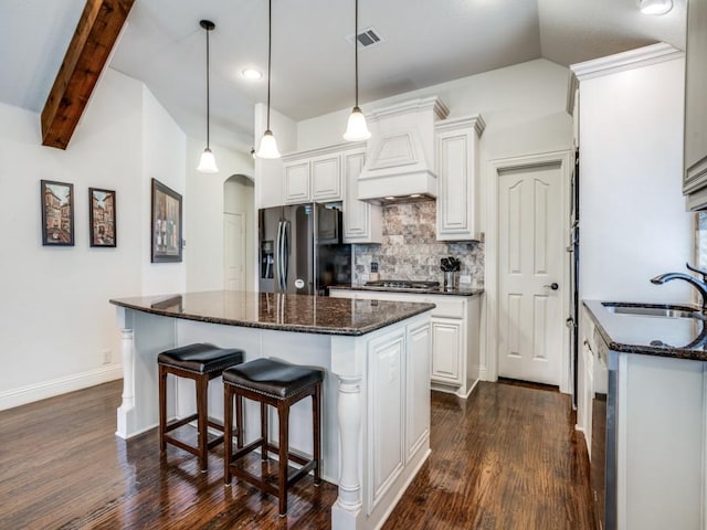 kitchen featuring visible vents, arched walkways, appliances with stainless steel finishes, custom exhaust hood, and a sink