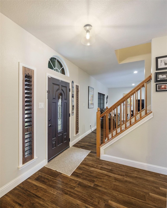 entryway featuring stairs, a textured ceiling, wood finished floors, and baseboards