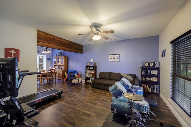 living area with ceiling fan with notable chandelier, visible vents, baseboards, and wood finished floors