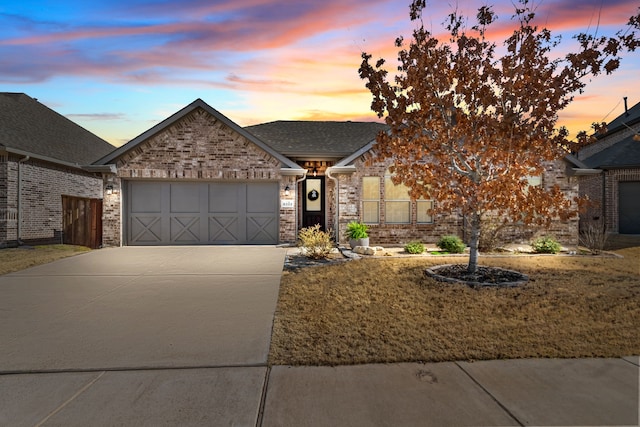 ranch-style house featuring a garage, concrete driveway, brick siding, and roof with shingles