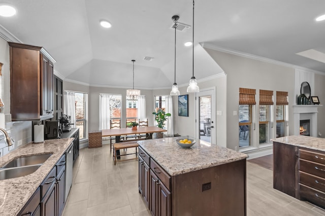 kitchen featuring dark brown cabinetry, a warm lit fireplace, visible vents, and a sink