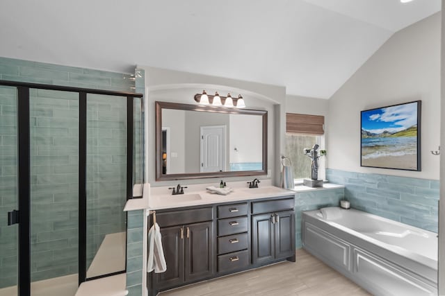 full bath featuring a bath, a shower stall, vaulted ceiling, and a sink