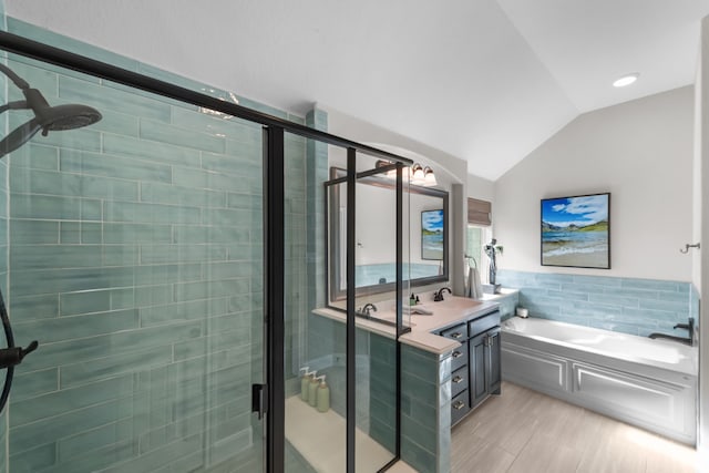 bathroom featuring tile walls, vaulted ceiling, a shower stall, vanity, and a bath