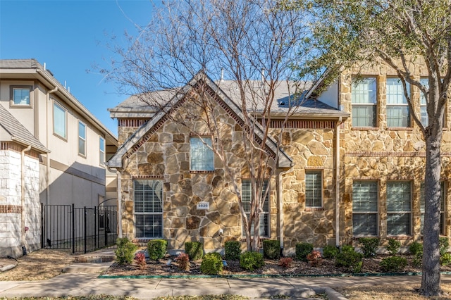 view of front facade with stone siding and fence