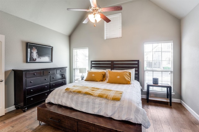 bedroom with high vaulted ceiling, ceiling fan, baseboards, and wood finished floors