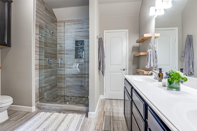 bathroom featuring toilet, a sink, baseboards, double vanity, and a stall shower