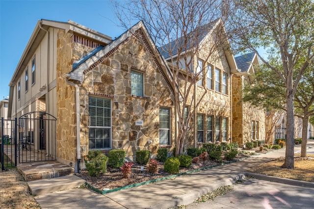 view of front of home featuring stone siding and a gate