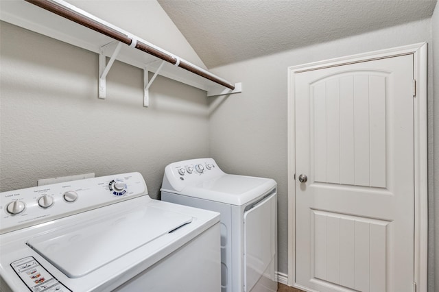 washroom with washing machine and dryer, laundry area, a textured wall, and a textured ceiling