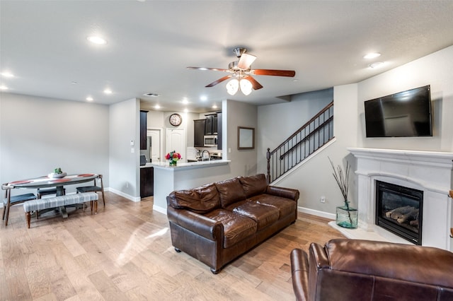 living area with recessed lighting, a premium fireplace, a ceiling fan, baseboards, and light wood-type flooring