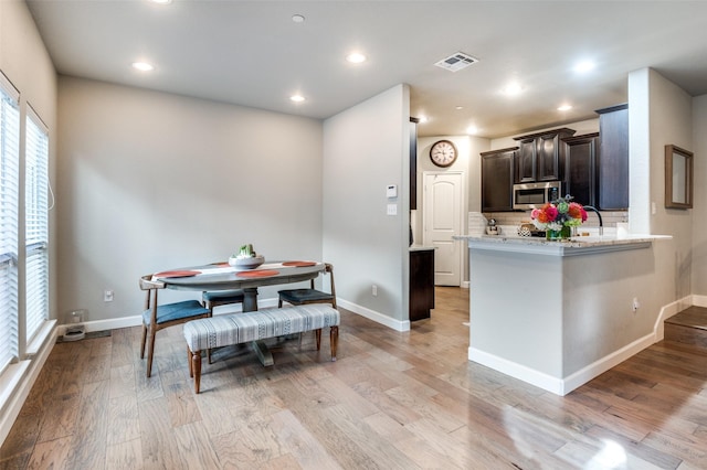 dining area with light wood-type flooring, visible vents, and baseboards