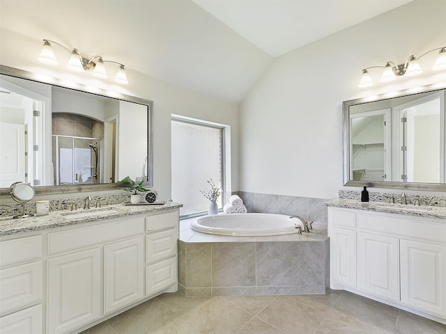 full bath with a stall shower, tile patterned flooring, vaulted ceiling, and a sink