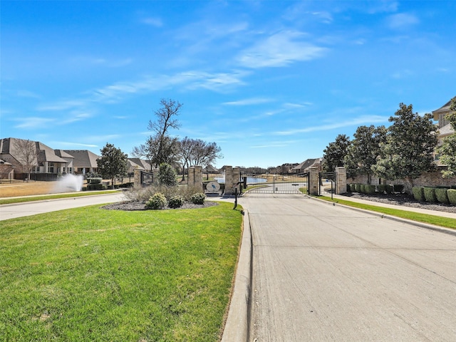 view of road with a gated entry, sidewalks, curbs, a gate, and a residential view