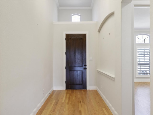 doorway to outside with a healthy amount of sunlight, light wood-type flooring, ornamental molding, and baseboards