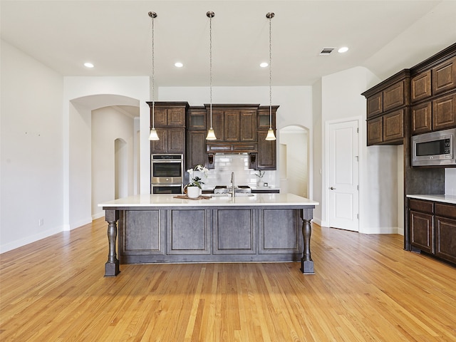 kitchen featuring arched walkways, light countertops, visible vents, appliances with stainless steel finishes, and a sink