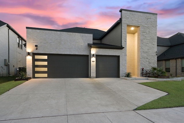 contemporary house featuring driveway, brick siding, and an attached garage