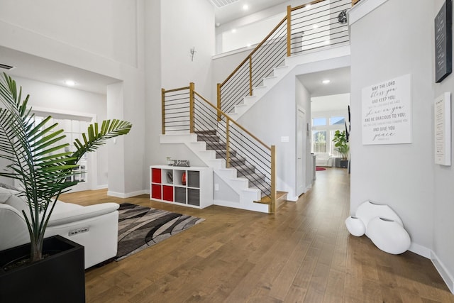 foyer featuring stairway, a high ceiling, baseboards, and wood finished floors