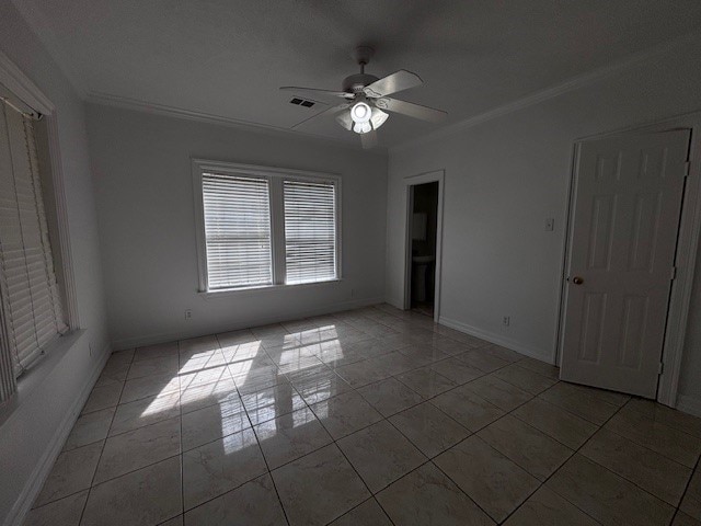 spare room featuring baseboards, a ceiling fan, visible vents, and crown molding