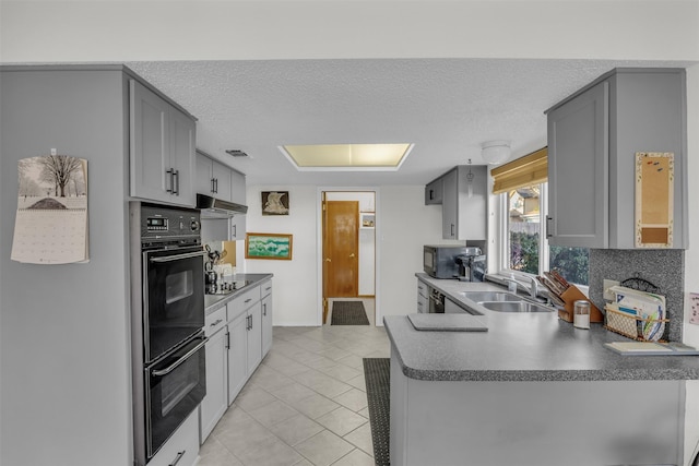 kitchen featuring gray cabinets, a sink, a textured ceiling, a peninsula, and black appliances