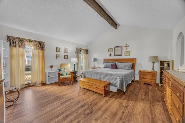 bedroom featuring arched walkways, vaulted ceiling with beams, a textured ceiling, and wood finished floors