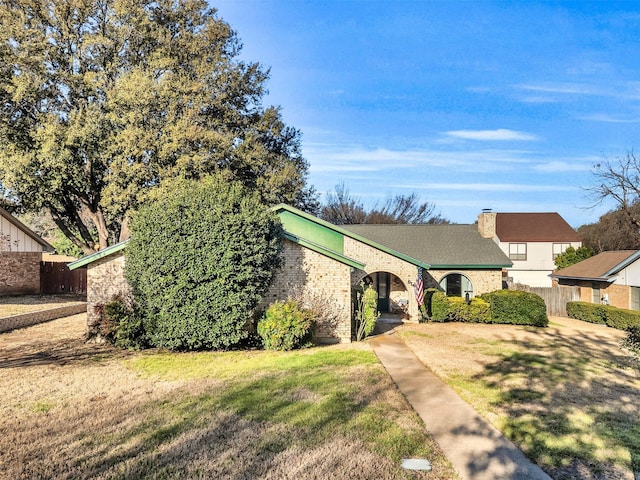 view of front of house featuring a front lawn, a chimney, fence, and brick siding