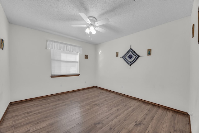 unfurnished room with a ceiling fan, a textured ceiling, baseboards, and wood finished floors