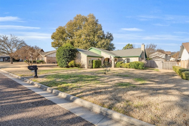 ranch-style house featuring a chimney, fence, and a front yard