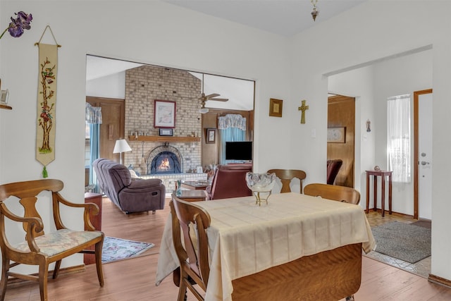 dining room with plenty of natural light, a fireplace, a ceiling fan, and light wood-style floors