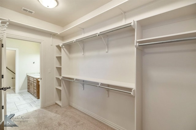 walk in closet featuring visible vents and light colored carpet