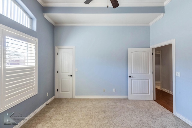 unfurnished bedroom featuring crown molding, carpet flooring, baseboards, and ceiling fan