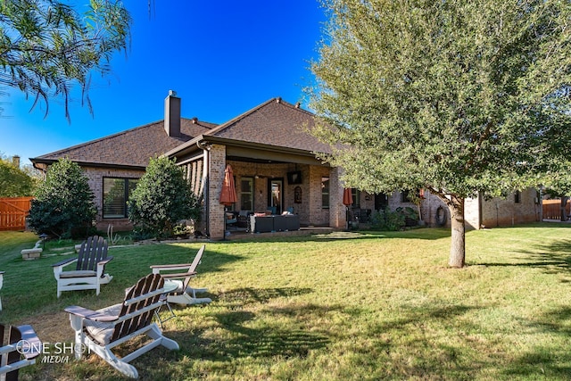 back of house featuring a patio, fence, a yard, a chimney, and brick siding