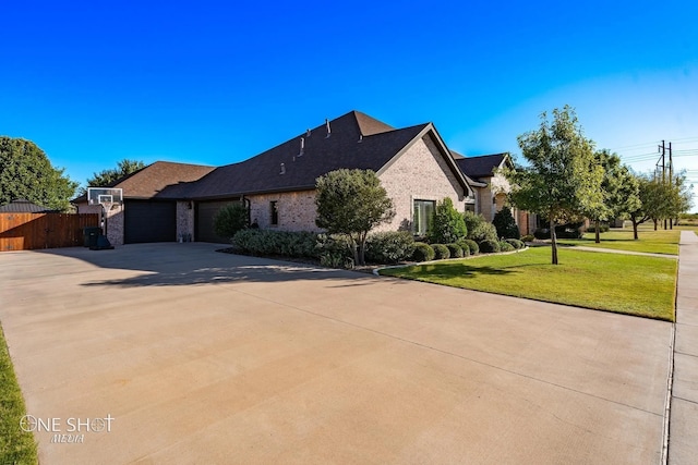 french provincial home featuring fence, concrete driveway, a front yard, a garage, and brick siding