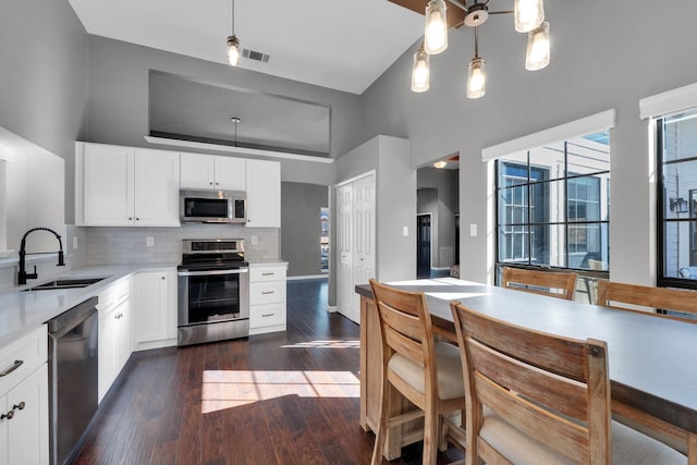 kitchen with tasteful backsplash, dark wood-style floors, appliances with stainless steel finishes, light countertops, and a sink