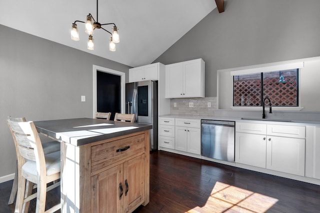 kitchen featuring dark wood-style flooring, a sink, white cabinets, appliances with stainless steel finishes, and decorative backsplash