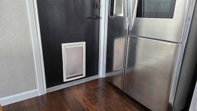 details featuring a textured wall, dark wood-style flooring, smart refrigerator, and baseboards