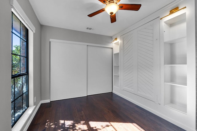 unfurnished room featuring built in shelves, visible vents, a ceiling fan, wood finished floors, and baseboards