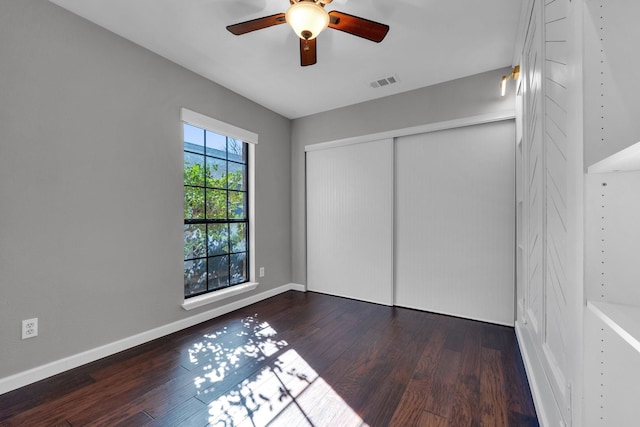 unfurnished bedroom featuring a closet, visible vents, baseboards, and wood finished floors