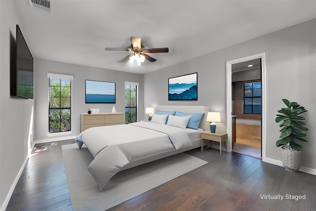 bedroom with ensuite bathroom, dark wood-style flooring, visible vents, and baseboards