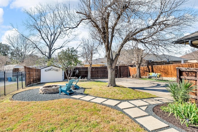 view of yard with fence private yard, an outdoor structure, a fire pit, and a storage unit