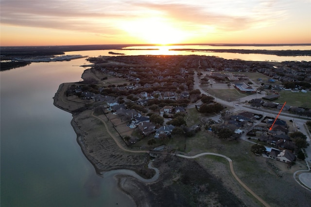 aerial view at dusk featuring a water view