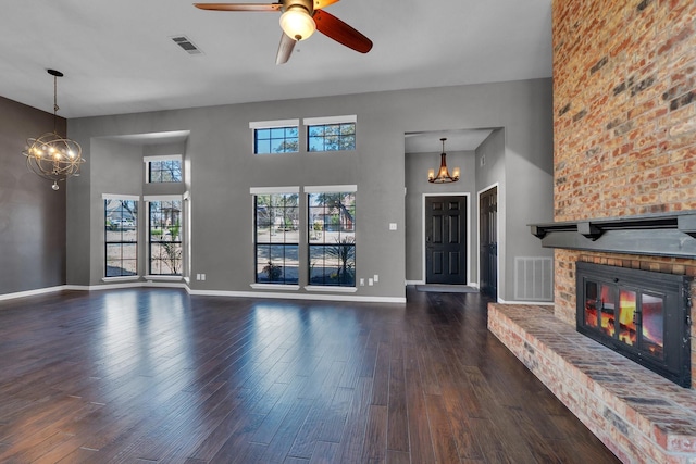 unfurnished living room featuring baseboards, a fireplace, visible vents, and wood finished floors