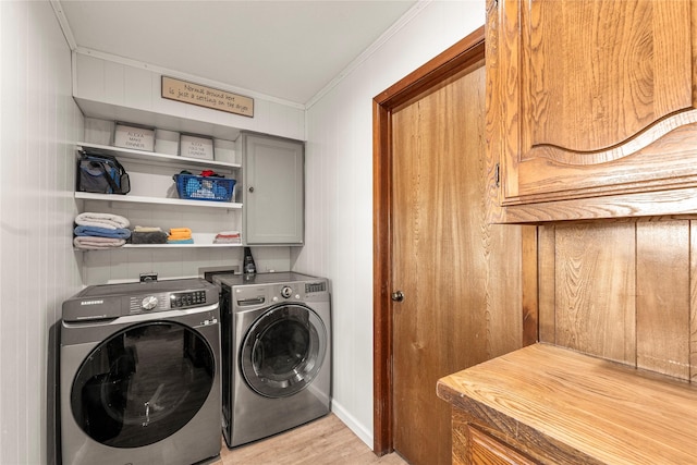 washroom with cabinet space, washing machine and dryer, ornamental molding, and light wood finished floors