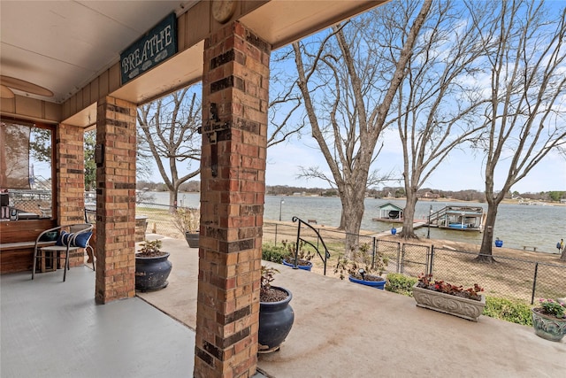 view of patio / terrace featuring a water view and fence