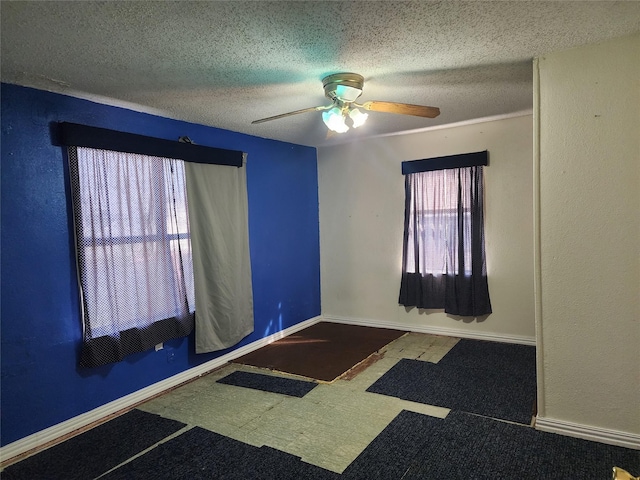 unfurnished room with a ceiling fan, a textured ceiling, and baseboards