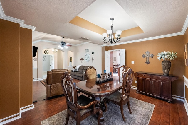 dining space featuring arched walkways, a tray ceiling, dark wood-style flooring, and visible vents