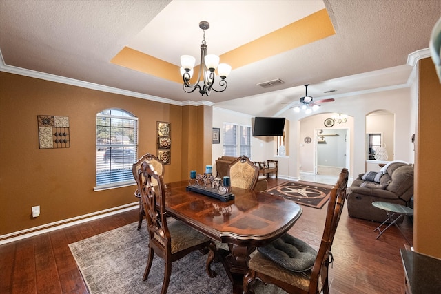 dining space with a tray ceiling, arched walkways, wood-type flooring, visible vents, and baseboards