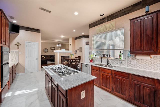 kitchen with marble finish floor, a fireplace, visible vents, appliances with stainless steel finishes, and a sink