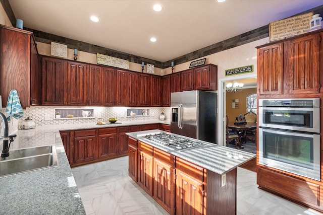 kitchen featuring appliances with stainless steel finishes, marble finish floor, a sink, and an inviting chandelier