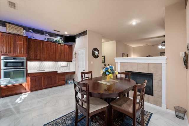 dining room featuring marble finish floor, a tile fireplace, and visible vents