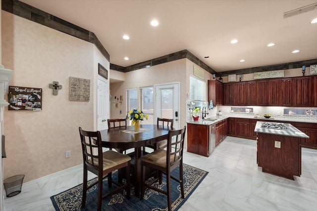 kitchen with recessed lighting, a sink, marble finish floor, light countertops, and a center island